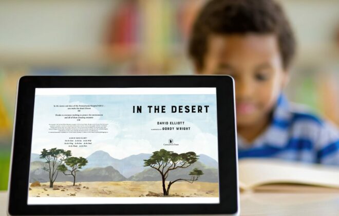 Student out of focus in background behind tablet in focus, with In the Desert book jacket displayed on device.