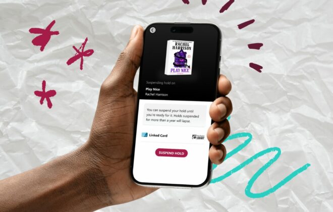 A hand holds a phone that has the new 'suspend hold' Libby feature pulled up on the screen