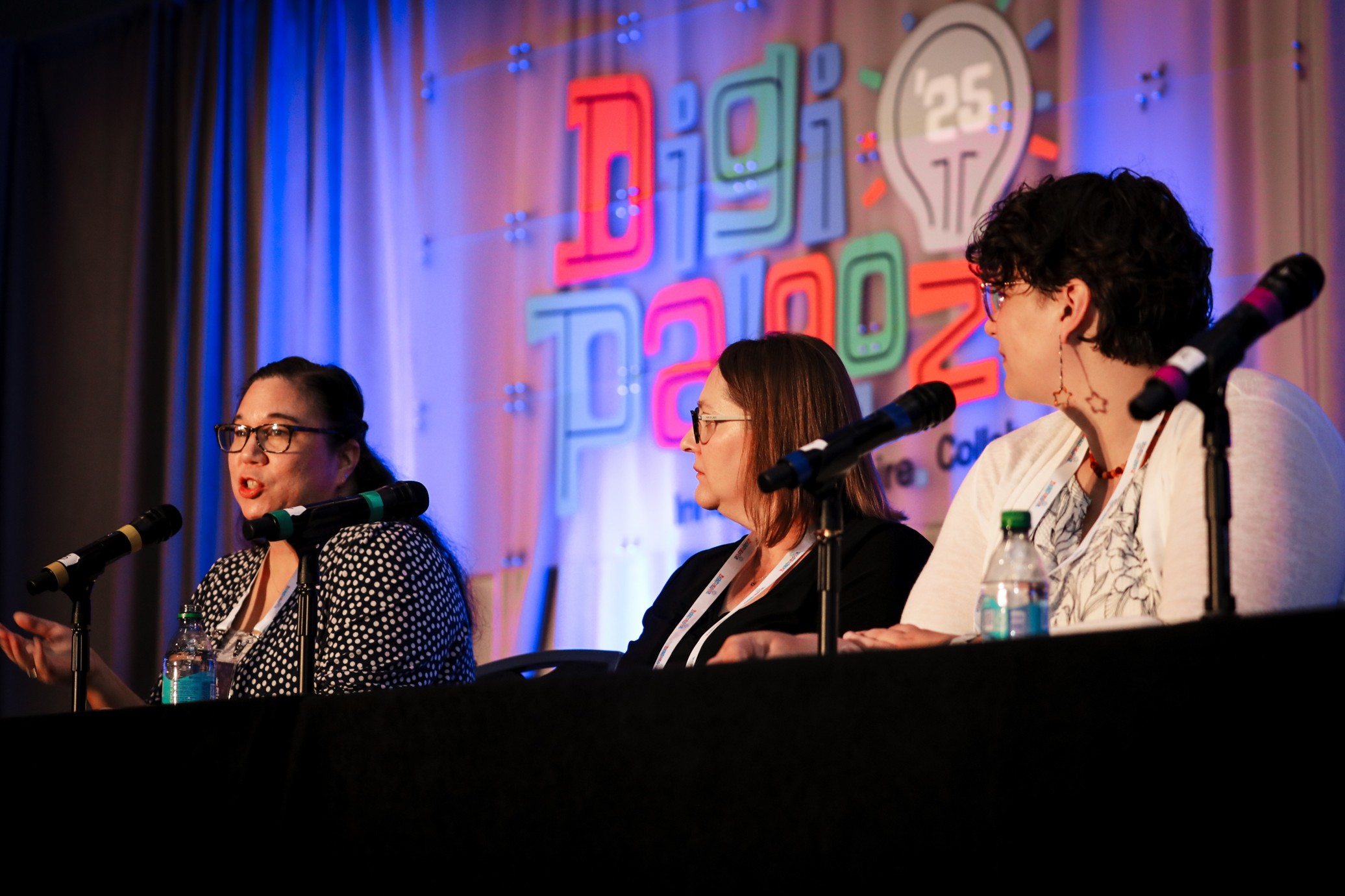 Three panelists on stage during a session